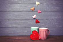 Two Cups And Color Hearts On Wooden Background
