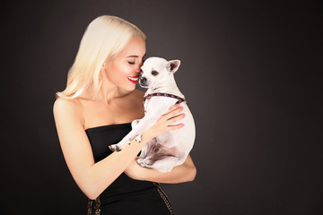 Wall Mural - Beautiful girl holding cute dog on dark background