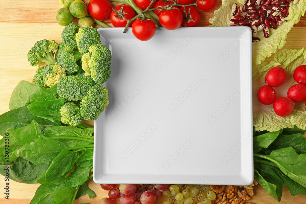 Empty plate with fruits and vegetables on wooden background