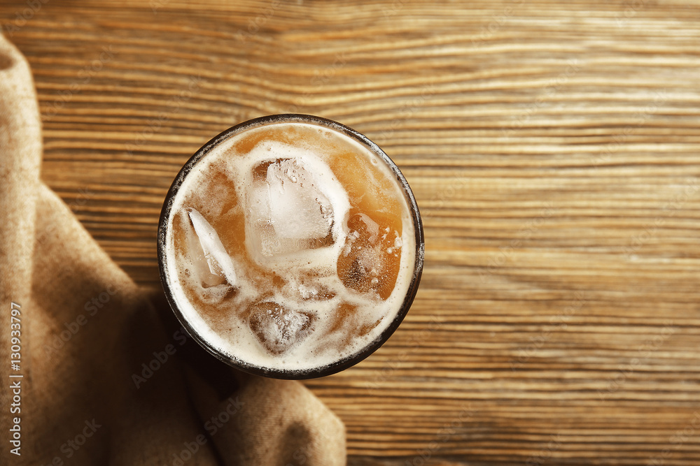 Glass of cold coffee on wooden background
