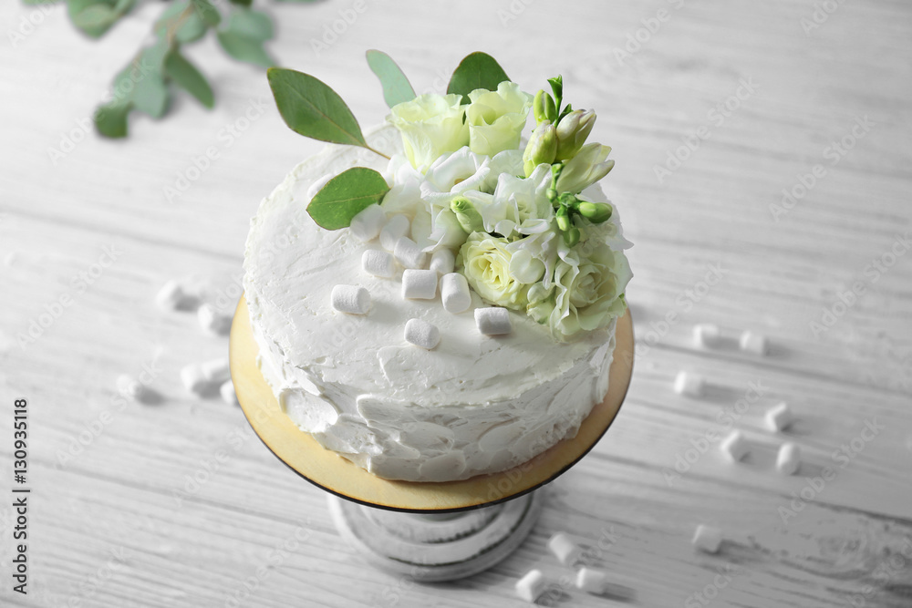Delicious cake decorated with marshmallows and flowers on wooden table