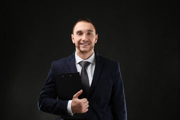 Poster - Young business coach with clipboard standing on black background