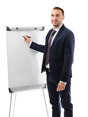 Poster - Young businessman standing near flip chart on white background