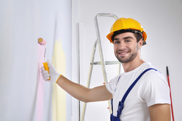 Canvas Print - Young worker painting wall in room