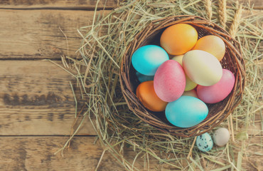 Wall Mural - Wicker basket with colorful Easter eggs on wooden table