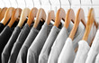 Black, grey and white t-shirts on hangers, close up view
