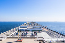 Panoramic Bird Eye Top Aerial View With Beautiful Sea Level With Highway Road Under Dramatic Clear Glow And Fantasy Blue Sky In Umi Hotaru Parking Area Island Tokyo Bay Aqua Line, Japan