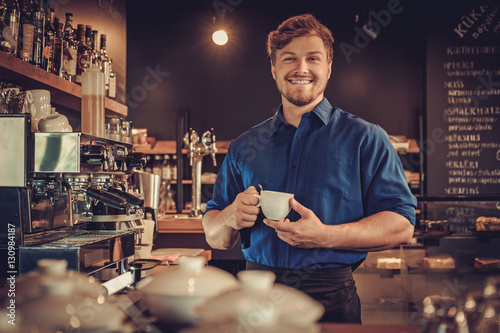 Fotografie, Obraz Handsome barista tasting a new type of coffee in his coffee shop
