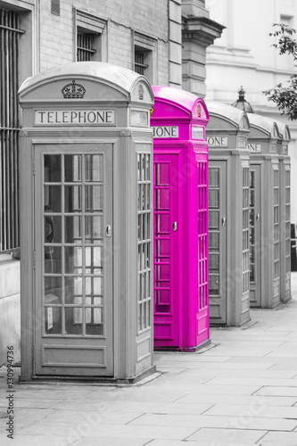 Fototapeta na wymiar Five Red London Telephone boxes all in a row, in black and white with one booth in pink