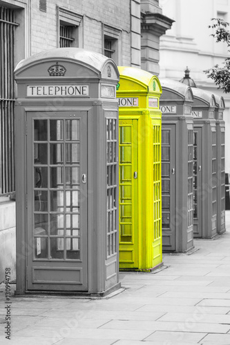 Naklejka na drzwi Five Red London Telephone boxes all in a row, in black and white with one booth in yellow