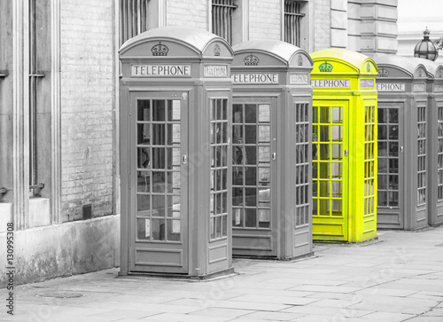 Naklejka na drzwi Five Red London Telephone boxes all in a row, in black and white with one booth in yellow