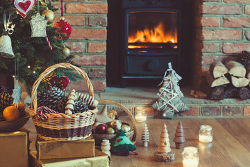 Wall Mural - Christmas decorations in the basket in front of the fireplace with candles and baubles, selective focus; dark vintage style toned photo