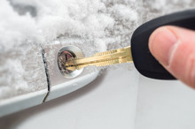 Close-up Of A Key Inserted Into The Lock Of Frozen Car Door In Winter