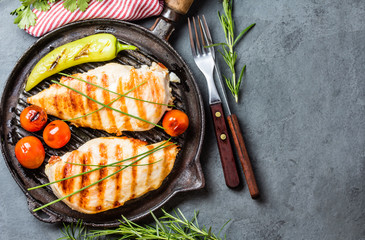 Grilled chicken fillets, chili and tomatoes on grill iron pan