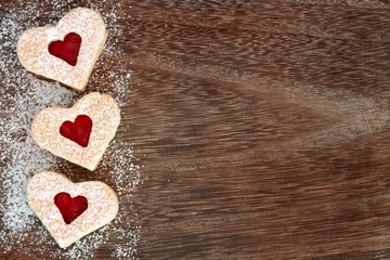 Wall Mural - Heart shaped Valentines Day cookies side border with powdered sugar over a rustic wood background