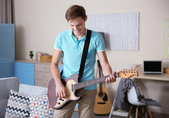 Wall Mural - Young man playing guitar in a room