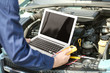 Mechanic using computer diagnostics while repairing car