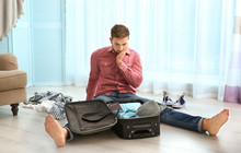 Young Man Sitting Beside Suitcase On Floor