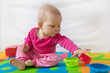 © Ivica Drusany - Cute bare feet  baby girl in pink clothes sitting on colorful puzzle play mat and playing with toys.