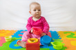 © Ivica Drusany - Cute bare feet  baby girl in pink clothes sitting on colorful puzzle play mat and playing with toys.