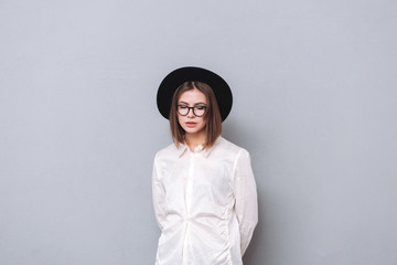 Wall Mural - Portrait of a casual girl wearing hat and eyeglasses standing