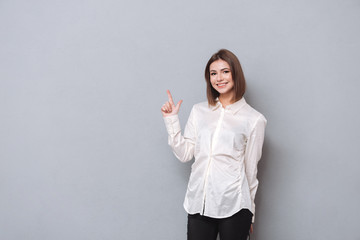 Wall Mural - Portrait of a smiling girl in shirt pointing finger up