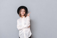 Woman In Hat Pointing Finger Away And Looking At Camera