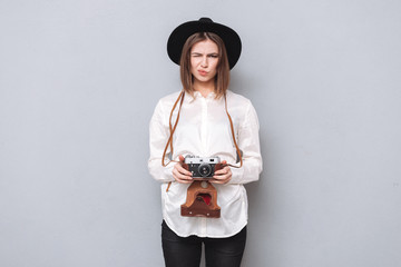 Sticker - Funny frustrated girl in hat standing and holding retro camera