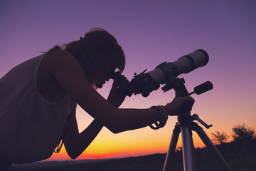 Wall Mural - girl looking at the stars through a telescope.