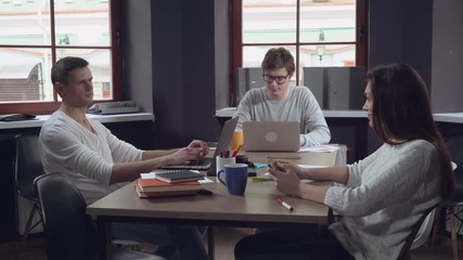 Aufkleber - Meeting young business people in the contemporary office. Professional man and woman discussing project. Smiling employees in startup company sitting at the working place using modern devices