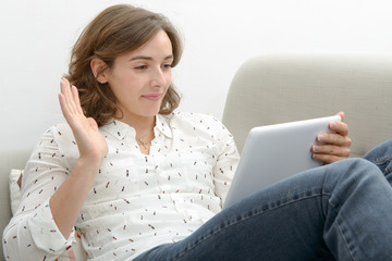 Wall Mural - Beautiful young woman woman with a tablet in the sofa