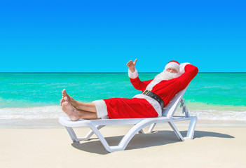 Canvas Print - Santa Claus thumbs up gesturing on sunlounger at tropical beach