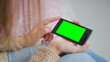 © zyabich - Woman looking at smartphone with green screen. Close up shot of woman's hands with mobile
