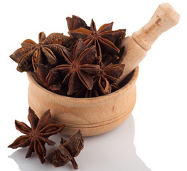 Star anise in a wooden bowl on a white background.