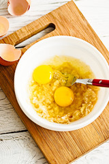 Wall Mural - Mixing ingredients for paleo pancakes in white bowl - eggs, mashed banana on white rustic wooden background.  Close up