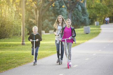 A women and her children riding together outdoors on a paved bike pathway. Smiling and having fun together at a outdoor nature park