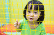 Leinwandbild Motiv Happy Asian Chinese little girl playing behind the net