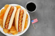 Hot dogs with mustard, chips and small USA flag on table