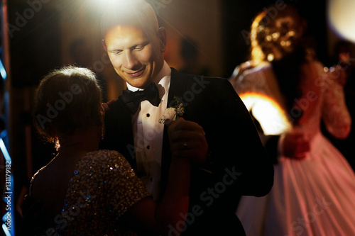 Cuadros en Lienzo Disco light shines over groom dancing with his mother