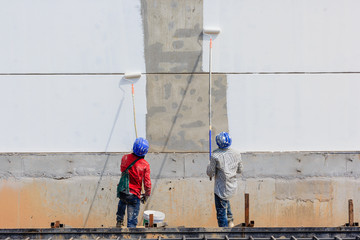 two workers are painting blank area on the wall