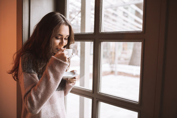 Wall Mural - Pretty lady sitting at table in cafe while drinking coffee