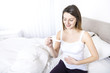 © Louis-Paul Photo - Young woman in bedroom at home wearing in white check pregnant test