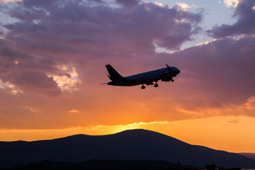 Wall Mural - Passenger airplane flying in the sky at sunset