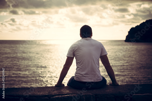Fotografie, Obraz Lonely man looking with hope at horizon with sunlight during sunset with effect