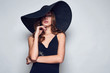 © micro - Elegant beautiful woman in a black dress and hat