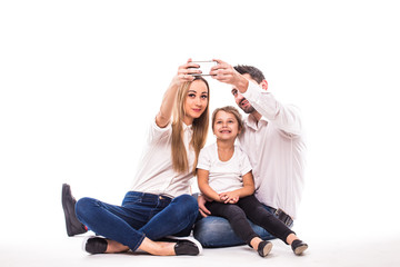 Happy family on white background. Mother, father and daughter take selfie on phone