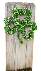 Foil St. Patrick's Day shamrock attached ot wooden post. Isolated.