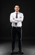 © Africa Studio - Young business coach with crossed hands standing on black background