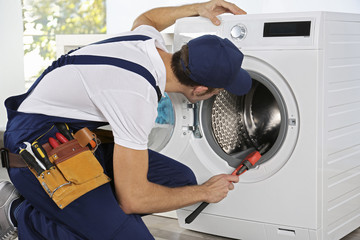 Wall Mural - Plumber repairing washing machine