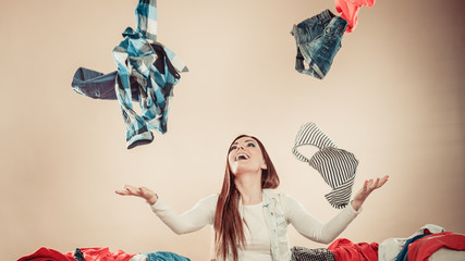 Happy girl sit on sofa and throw clothes in air.